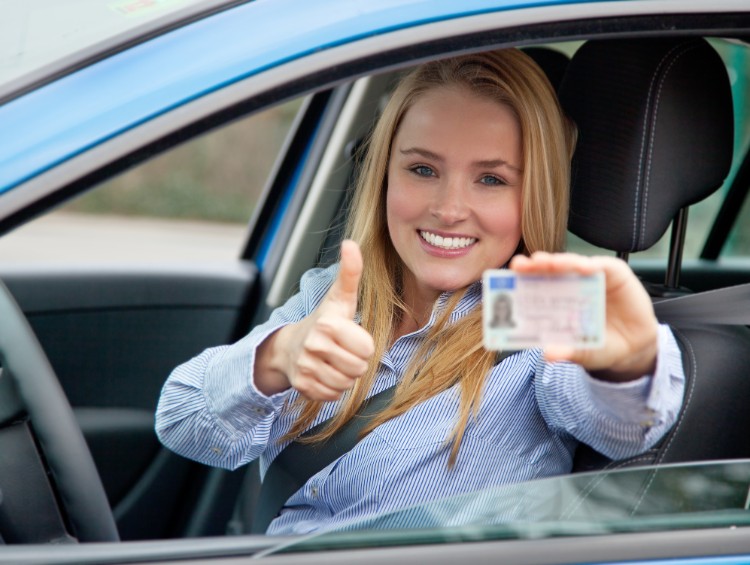 Woman holding licenses in car